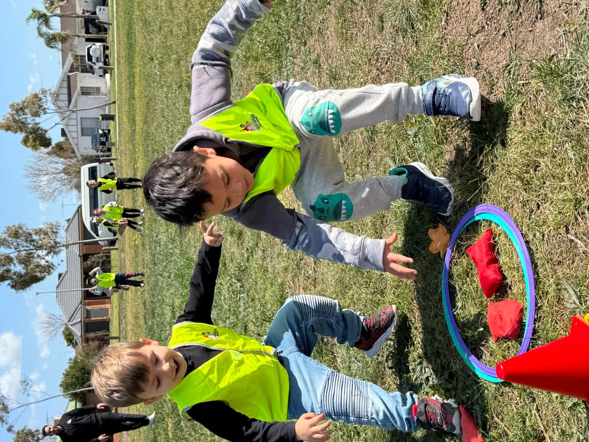 Children playing in a garden activity area with tyres and natural elements.