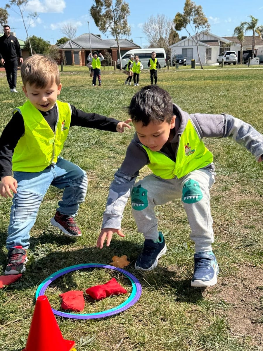 Children playing in a garden activity area with tyres and natural elements.