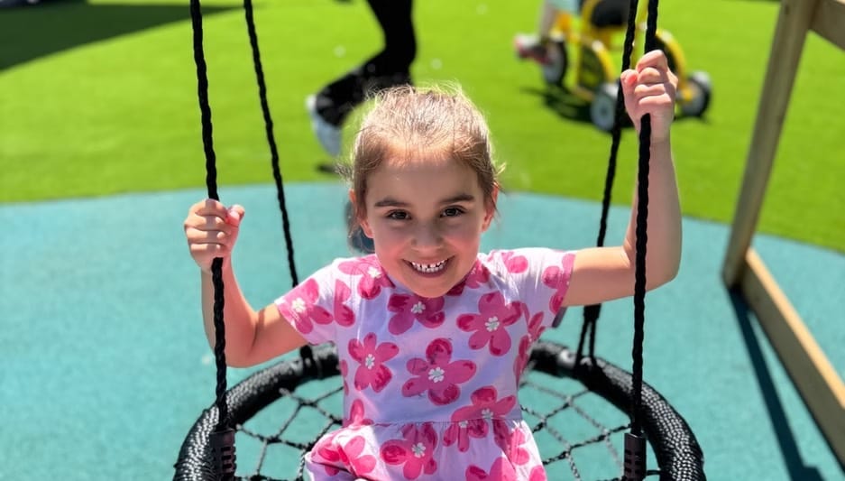 A child smiling on the outdoor nest swing at the Hoppers Crossing centre.