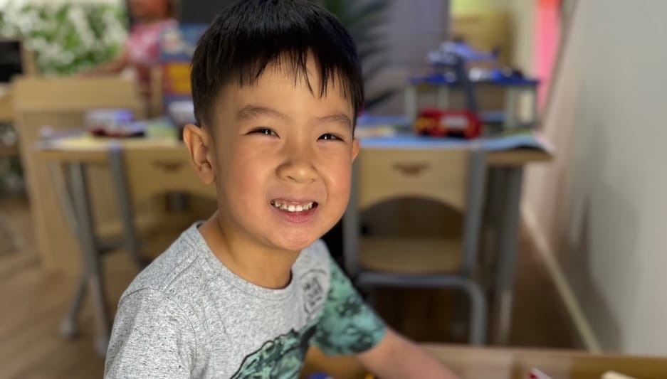 A smiling child indoors during a calm classroom moment at Kids Kingdom.
